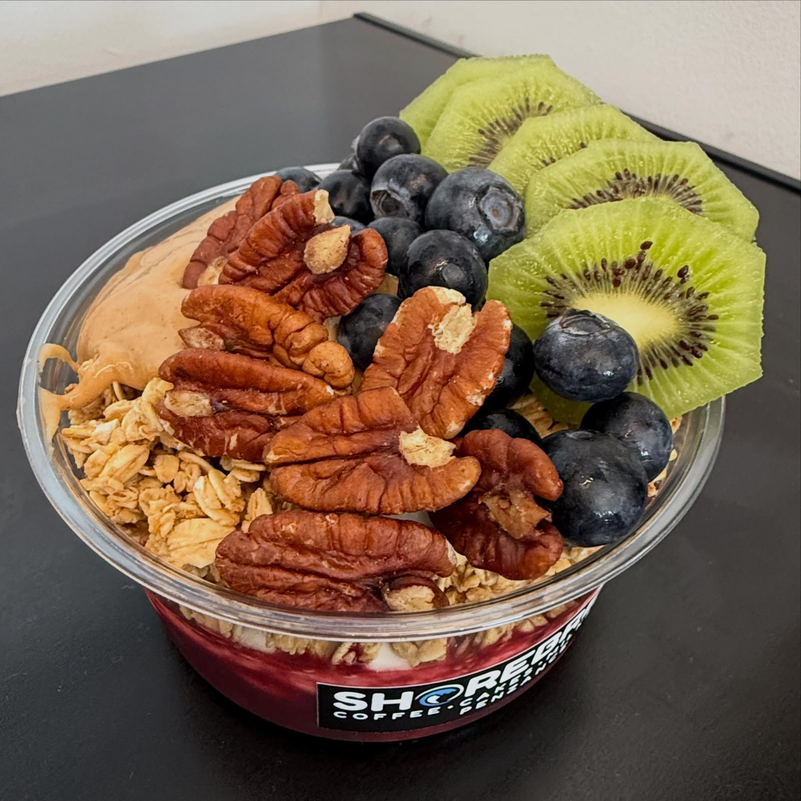 Granola bowl topped with pecans, blueberries and kiwi