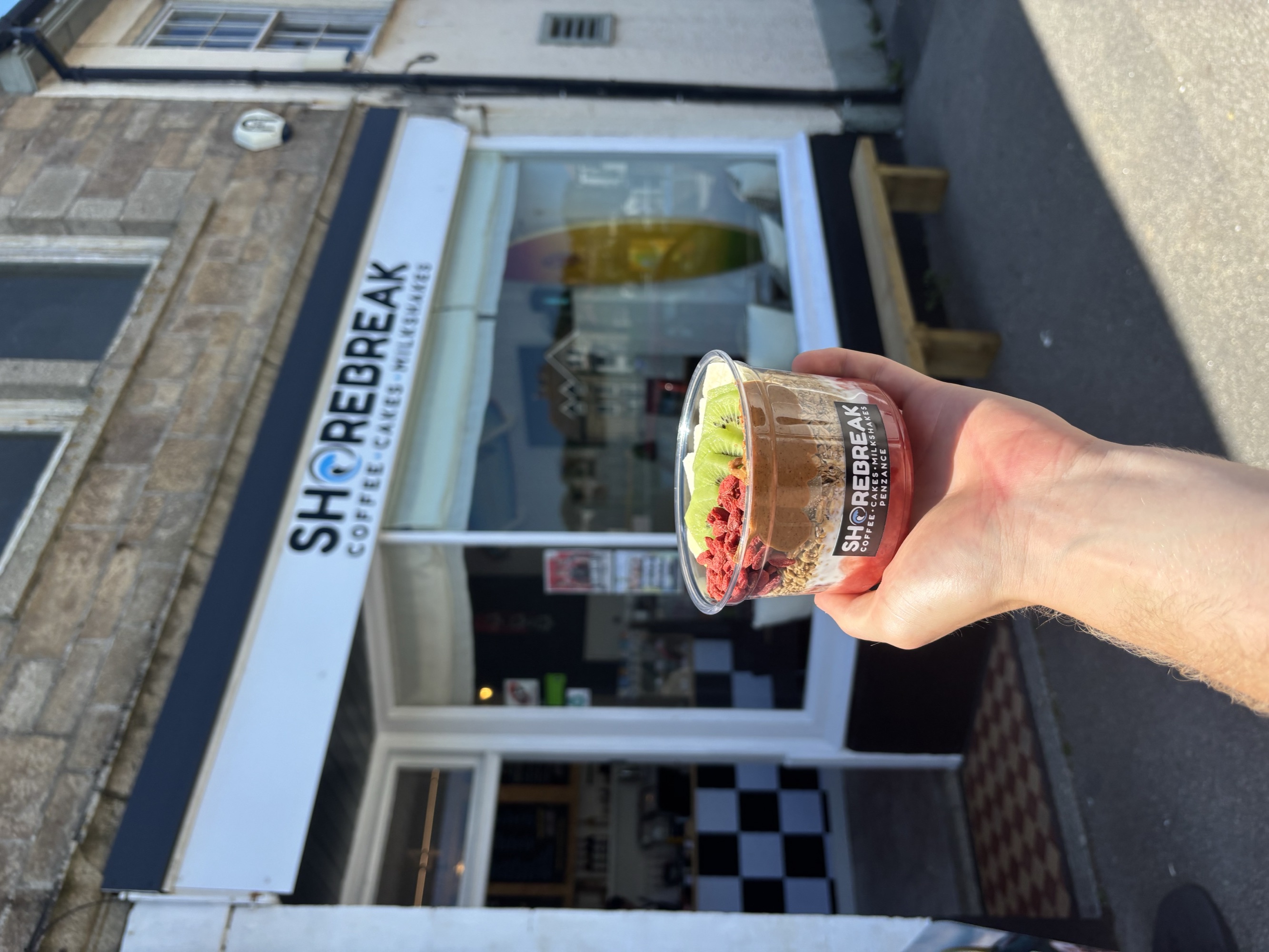 Granola bowl held up outside Shorebreak on a sunny day